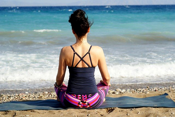donna medita sulla spiaggia in centratura